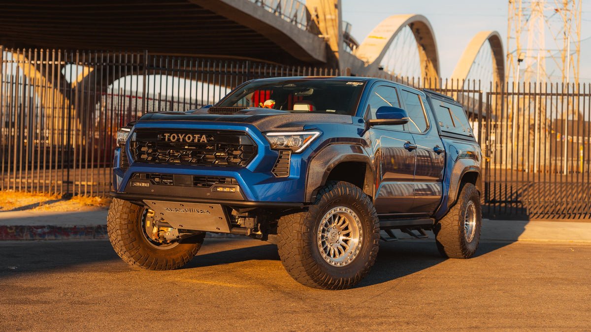 Blue 4th Gen Toyota Tacoma on Lock Off-Road Grit wheels at sunset, front three-quarter view